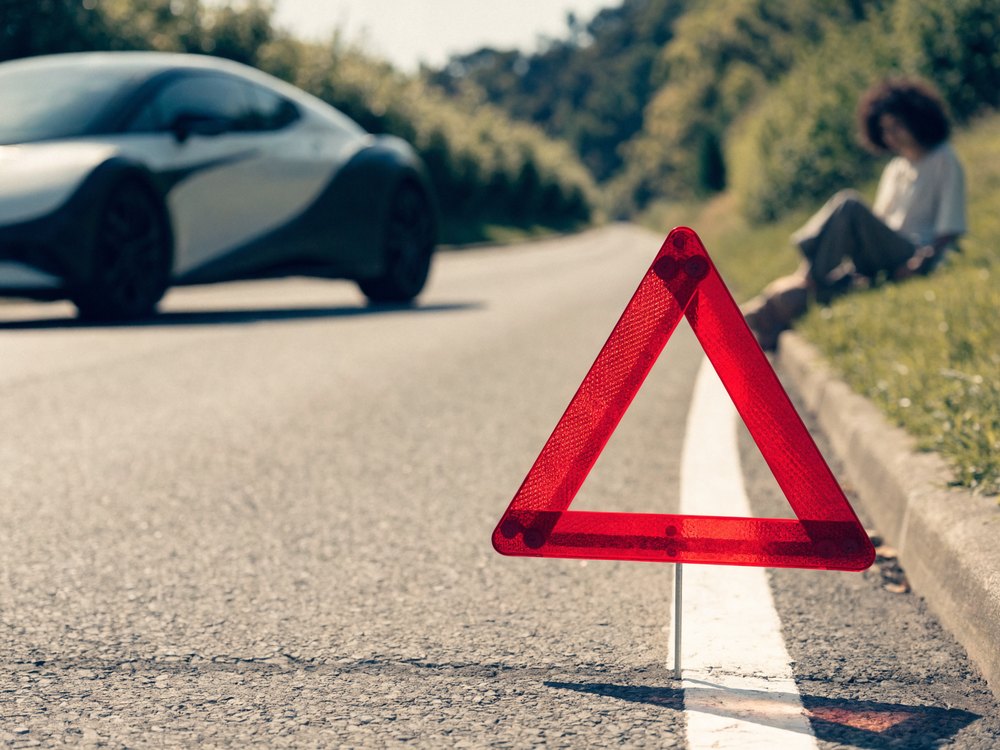 Warndreieck vor einem Pannenfahrzeug am Straßenrand